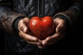 Mans hands embrace a red heart, expressing care and devotion