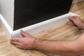 Mans hands fitting skirting board