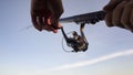 Mans hands spinning fishing reel, catching fish, gear and supplies, close up Royalty Free Stock Photo