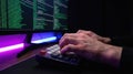 Mans hands typing on mechanical keyboard with glowing code on computer screen, dark room with neon lighting Concept of programming Royalty Free Stock Photo
