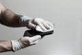 A mans hands wearing latex gloves wiping off his cell phone with a disinfecting wipe during the Covid 19 pandemic