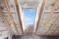 Mansard with environmentally friendly and energy efficient skylight window against blue sky. Room under construction with wooden b