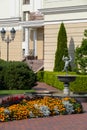 Mansion in light colors with well-kept flower beds, pyramidal thuys, a fountain with a statue of a boy and beautiful Royalty Free Stock Photo