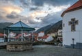 Manteigas village bandstand with houses and mountains in the background under dramatic sky, cross of StÃÂª Maria Mother Church