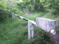 Manual barrier on forest track with stone blocking system. Exuberant vegetation environment. Manually operated level crossing