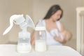 Manual breast pump and bottle with breast milk on the background of mother holding in her hands and breastfeeding baby. Maternity Royalty Free Stock Photo