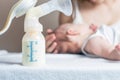 Manual breast pump with milk, mother and baby at background Royalty Free Stock Photo