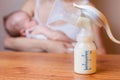 Manual breast pump with milk, mother and baby at background Royalty Free Stock Photo