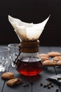 Manual coffee brewing. Hot aromatic coffee dripping through paper filter on dark wooden table