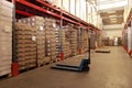 Manual forklift near storage racks in warehouse. Logistics concept