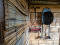 A manual lawn mower and a basic black grill hanging from a cane wall