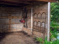 A manual lawn mower, a basic black grill and a vintage bed hanging from a cane wall in a rustic shed