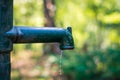 Manual old green and rusty water lever pump with water pouring out of the spout, last drop of water, drought Royalty Free Stock Photo