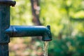 Manual old green and rusty water lever pump with water pouring out of the spout