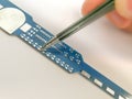 Manual PCB assembly process. Male hand holding tweezers with 0805 SMD resistor