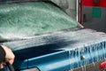 Manual washing of the car with water under pressure on the car wash outside. Summer car wash. Cleaning the car with high-pressure