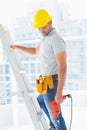 Manual worker with drill machine climbing ladder Royalty Free Stock Photo