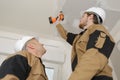 Manual worker drilling ceiling with drilling machine