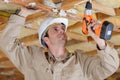 Manual worker drilling ceiling with drilling machine