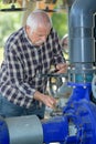 Manual worker turning cut-off valve at plant Royalty Free Stock Photo