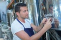 Manufacturer filling beer into glass from storage tank at brewery Royalty Free Stock Photo