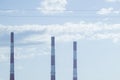 Red and white long three factory pipes with the blue sky in the background Royalty Free Stock Photo