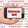 Manufacuring concept: Hand Holding Smartphone with Conveyor Belt on display Royalty Free Stock Photo