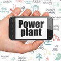 Manufacuring concept: Hand Holding Smartphone with Power Plant on display Royalty Free Stock Photo