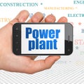 Manufacuring concept: Hand Holding Smartphone with Power Plant on display Royalty Free Stock Photo