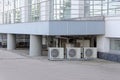 Many air conditioners installed in the same place under the porch of the office building.