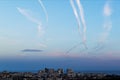 Many airplane contrails in a clear sky over the city. Jets of airplane in the blue sky