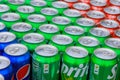 Many aluminum cans of sparkling drinks Sprite, Coca-Cola, Pepsi staying in a rows.