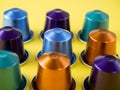 Many aluminum coffee capsules are displayed in a row on a yellow background. Food pattern. Capsules for the coffee machine