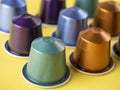 Many aluminum coffee capsules are displayed in a row on a yellow background. Food pattern. Capsules for the coffee machine