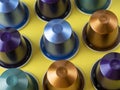 Many aluminum coffee capsules are displayed in a row on a yellow background. Food pattern. Capsules for the coffee machine