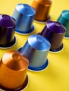 Many aluminum coffee capsules are displayed in a row on a yellow background. Food pattern. Capsules for the coffee machine