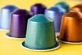 Many aluminum coffee capsules are displayed in a row on a yellow background. Food pattern. Capsules for the coffee machine