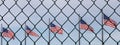 Many american flags behind barbed wire fence. Concept of border dispute and immigration controversy. USA travel and homeland secur Royalty Free Stock Photo