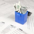 Many american tax blank forms and crumpled hundred dollar bill in trash bin