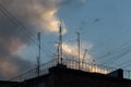many antennas on the roof of a multi storey house against the sky and clouds