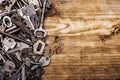 Many assorted old multi-colored metal antique vintage keys of different shapes laid out on wooden scratched table background. Home Royalty Free Stock Photo