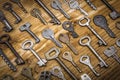 Many assorted old multi-colored metal antique vintage keys of different shapes on wooden scratched table background. Home security Royalty Free Stock Photo