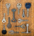 Many assorted old multi-colored metal antique vintage keys of different shapes on wooden scratched table background Royalty Free Stock Photo