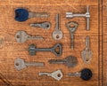Many assorted old multi-colored metal antique vintage keys of different shapes on wooden scratched table background Royalty Free Stock Photo
