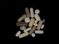 Many assorted pills jumbled together on a white surface - a combination of supplements and prescription drugs