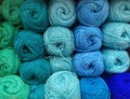 Many balls of wool yarn in natural shades of green and blue for knitting crocheting