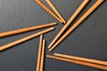 Many bamboo chopsticks on black slate background, textured, top view with opy space