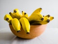 Many bananas in bowl on table viewed from side Royalty Free Stock Photo