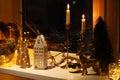 Many beautiful Christmas decorations, candlesticks and festive lights on window sill indoors Royalty Free Stock Photo