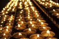 Many beautiful lit candles in a row glowing with a golden yellow light Royalty Free Stock Photo